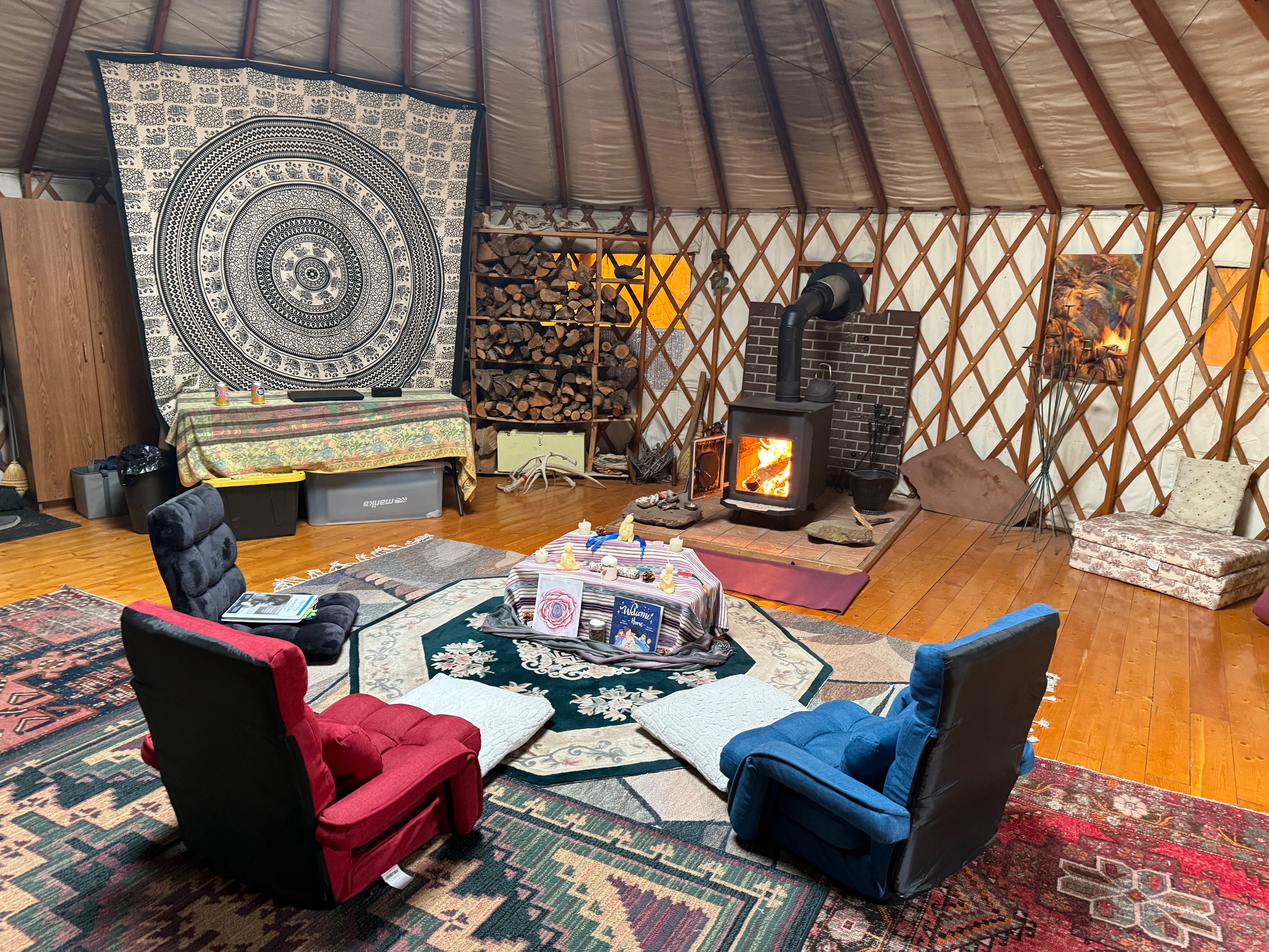 Cosy learning space set up in yurt with fire in wood stove.